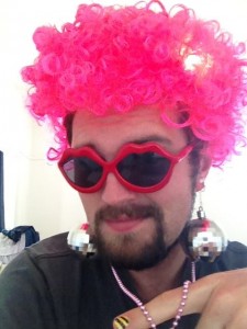A bearded man in a bright pink wig that has three different disco-related light settings